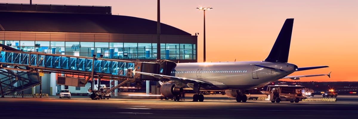 An aeroplane at an airport, pictured against a vivid sunset.