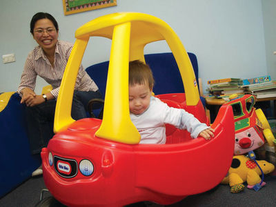 A small child sitting in a colourful toy car