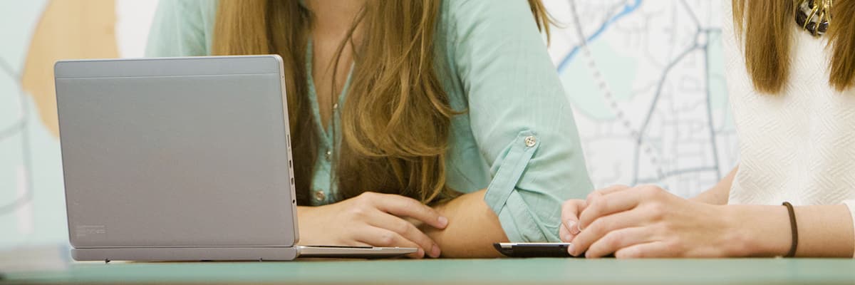 Two people work at a laptop.