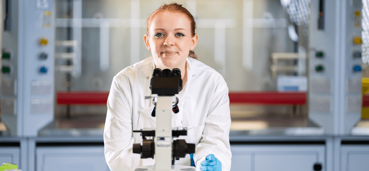 Student in the biosciences lab in front of a microscope