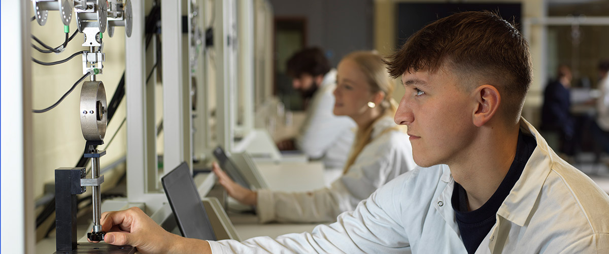 Three seated students using equipment in a laboratory
