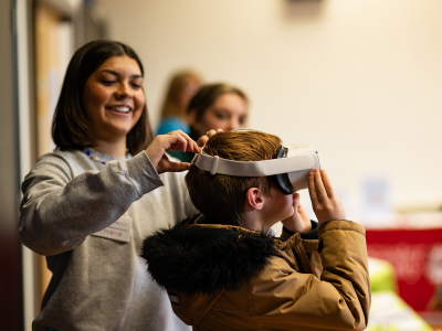 a child is helped to put on a VR headset