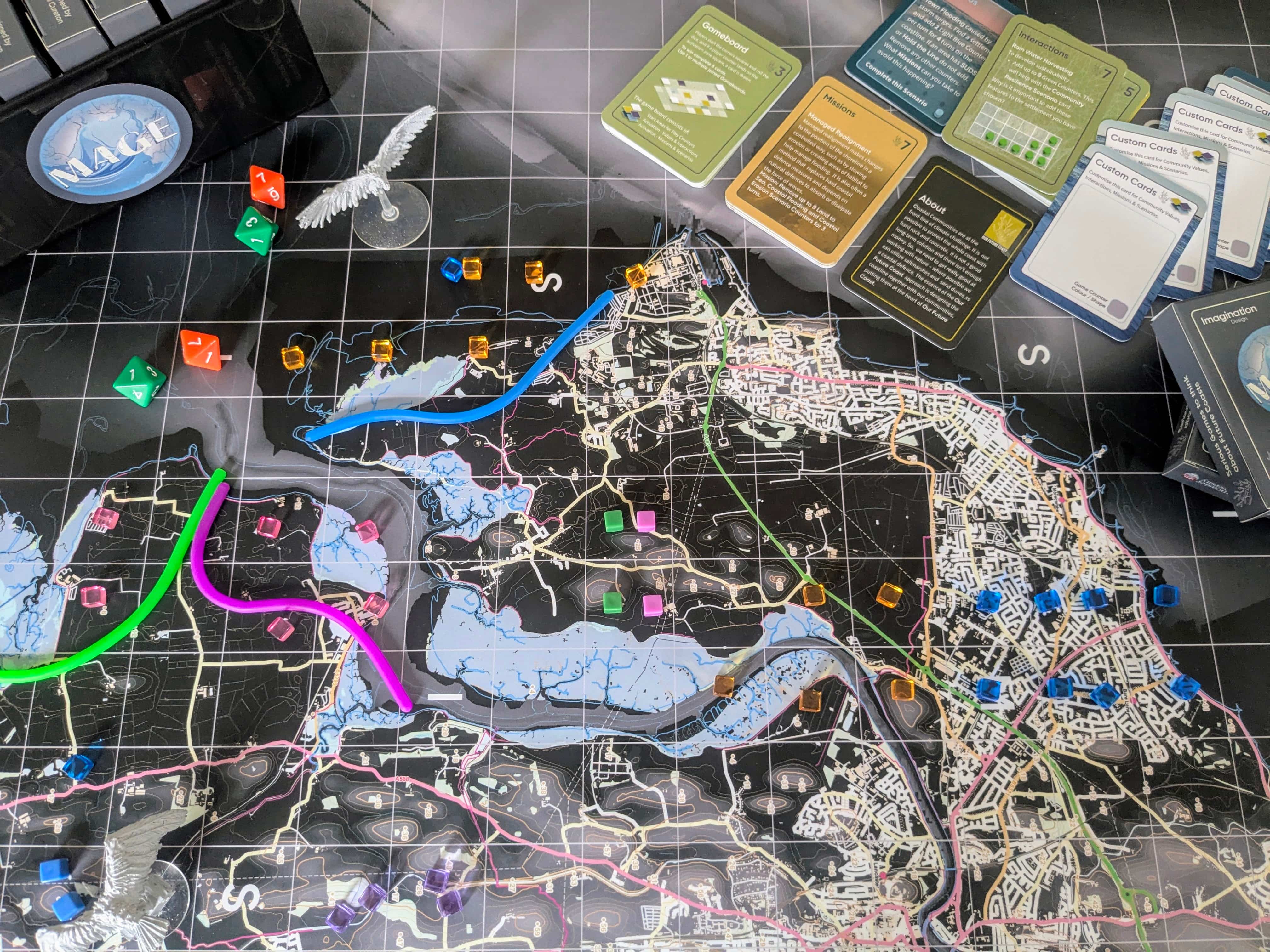 a board game showing a coastline with game cards and 8 sided dice