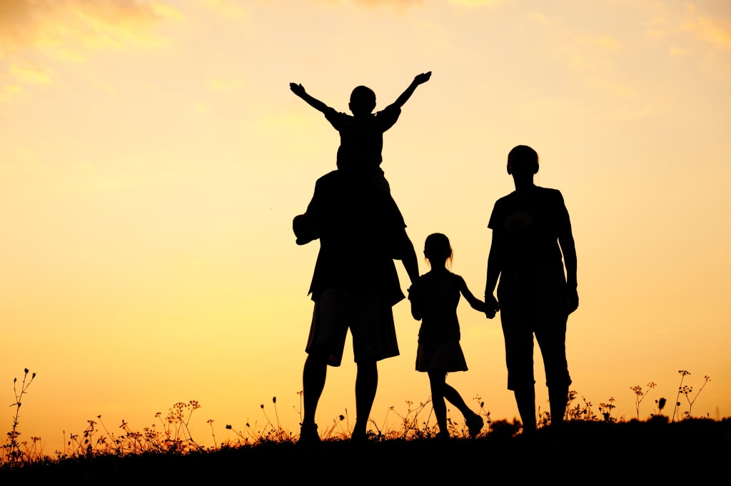 a family is silhouetted against a sunset