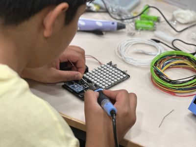 a boy uses a solder iron on a gaming toy