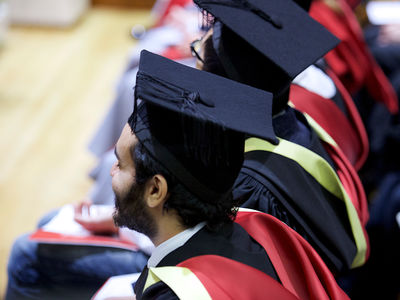 A group of graduates photographed from above at a graduation ceremony.