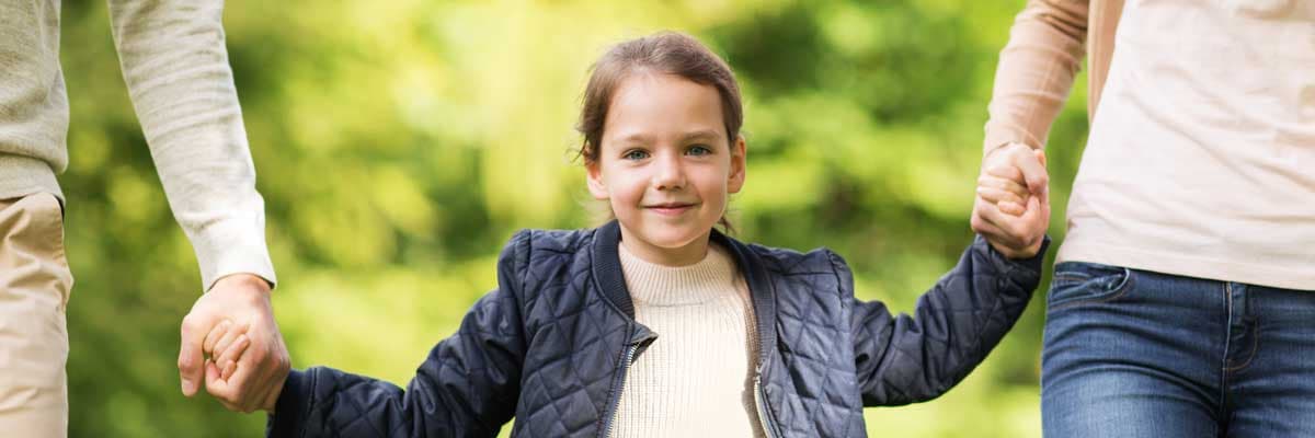  family walking in summer park girl holding hands with two adults
