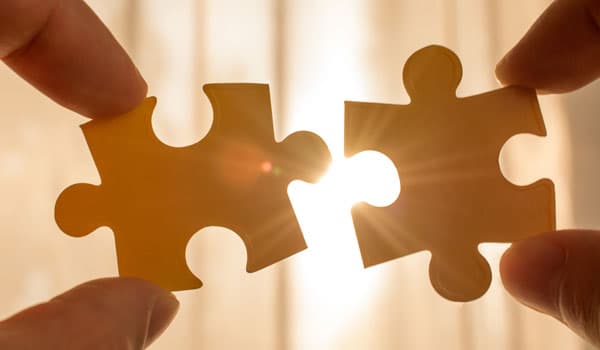 two hands trying to connect couple puzzle piece. with sunset background