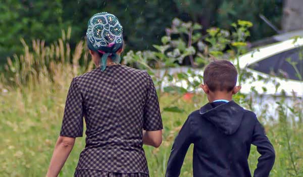 mother and son of Roma heritage walking in a field