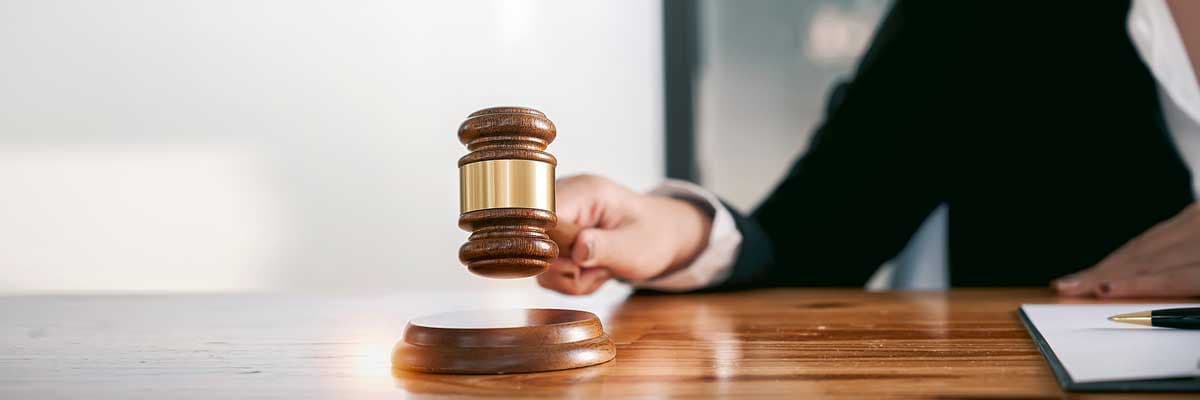 Woman judge hand holding gavel to bang on sounding block in the court room