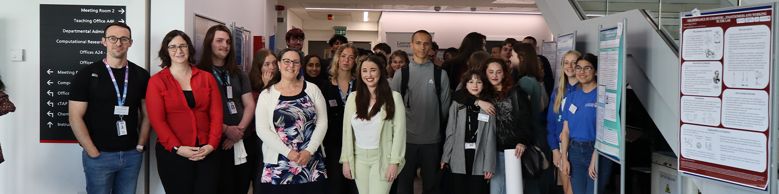 A group of students and staff at a university chemistry event with posters displayed