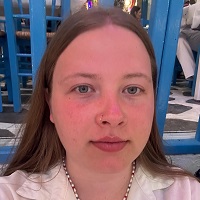 Close up of Amy Bellis holding a paper cup and straw in one hand and a tea light in the other. 