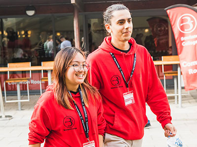 Two students wearing red hoodies and black lanyards