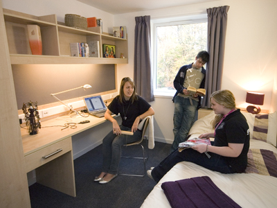 Three students chatting in a townhouse bedroom