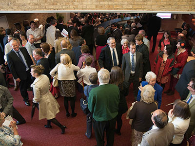 Crowd standing and chatting in a foyer.