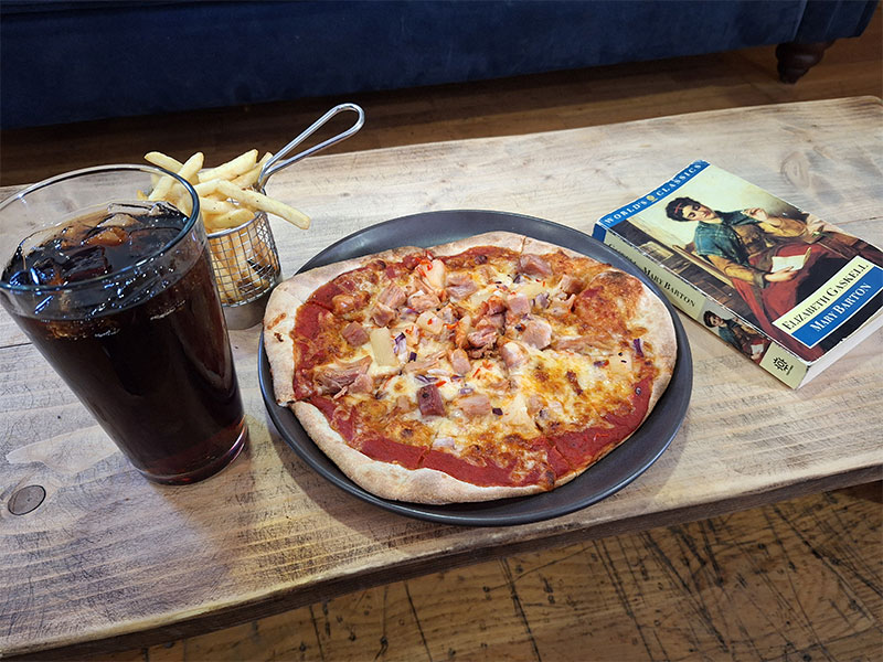 A pizza and fizzy drink on a cafe table. 