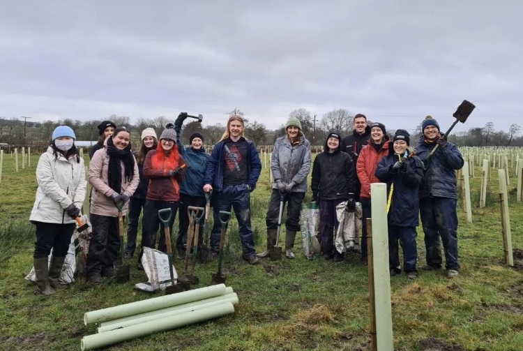 Student Lyea and other students standing together with planting equipment.