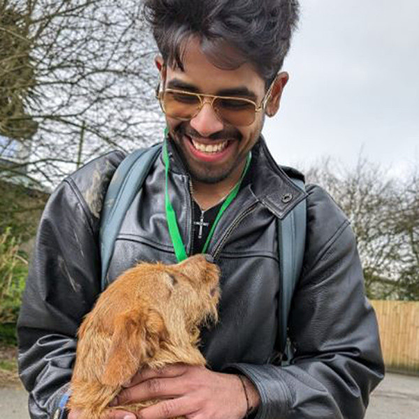 Student smiling and looking down at dog 