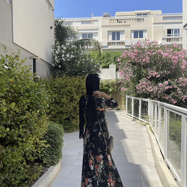 Student looking away from the camera surrounded by flowers