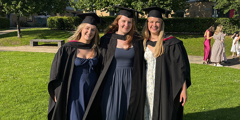 Ellie and two friends wearing their graduation caps and gowns.