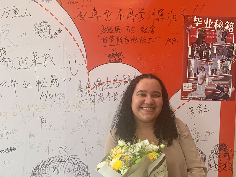 Lyea holding flowers after attending a graduation ceremony.