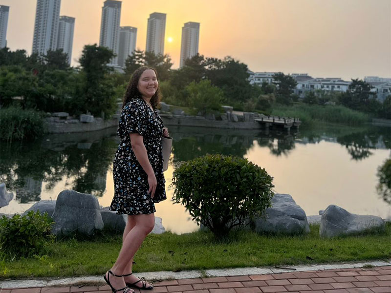 Student Lyea with buildings and sunset in the background.