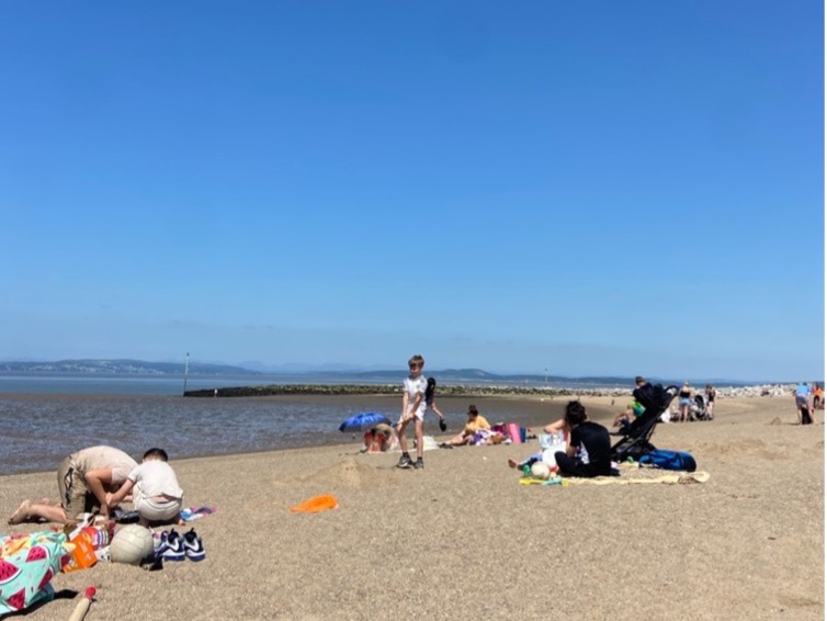 A sunny day with groups of people playing on the beach.