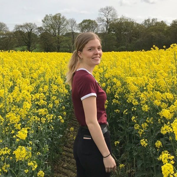 Female student standing in a field on a sunny day