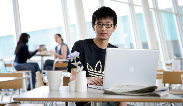 A student working at a laptop in cafe 21