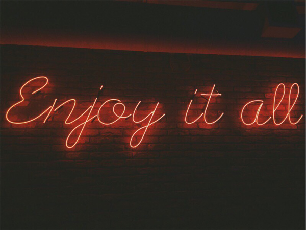 A neon light that reads - Enjoy it all