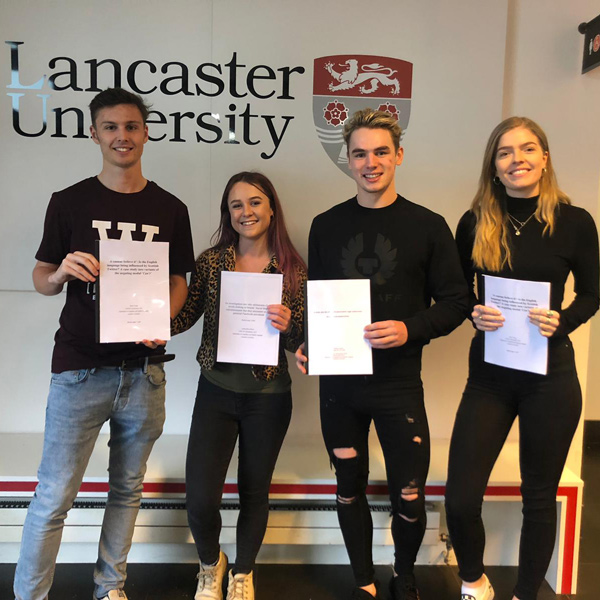 four students holding documents
