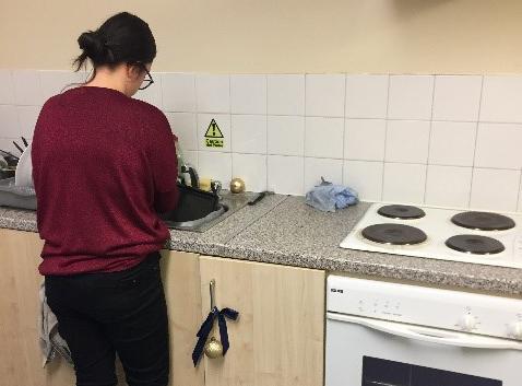 A female student facing away from the camera doing the washing up
