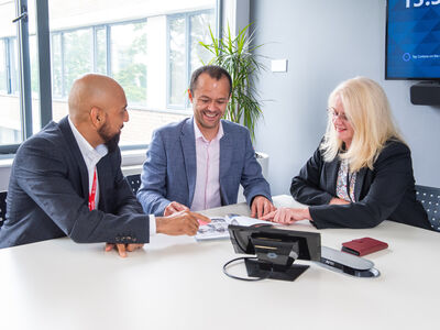 Three peole sat around a table having a discussion.