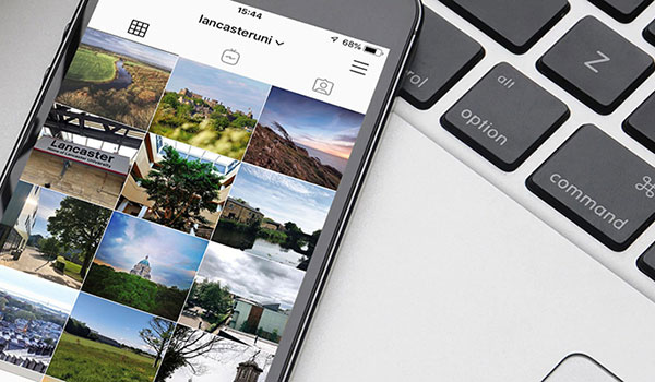 Part of laptop with mobile phone over it. Lancaster University Instagram account showing on mobile.
