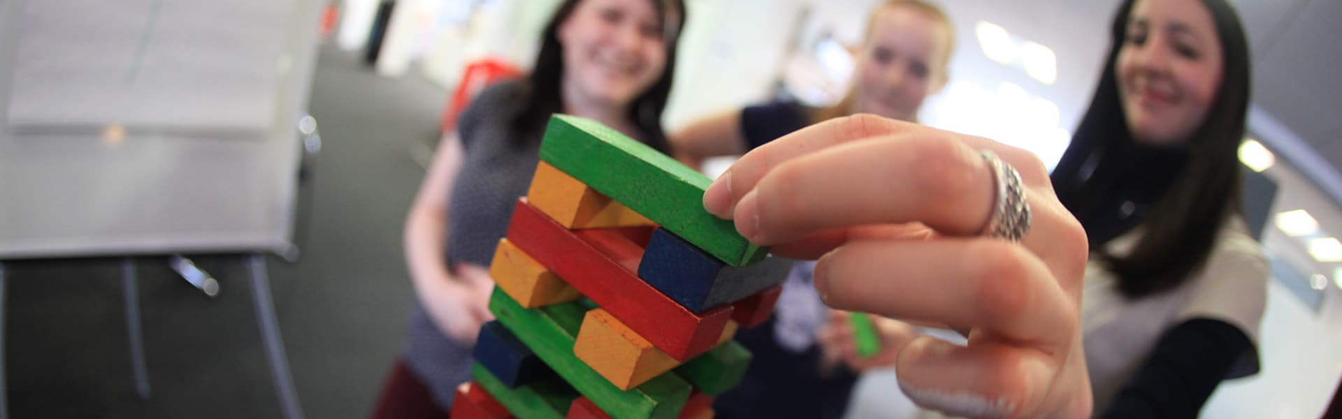 Two people watching someone place a puzzle brick