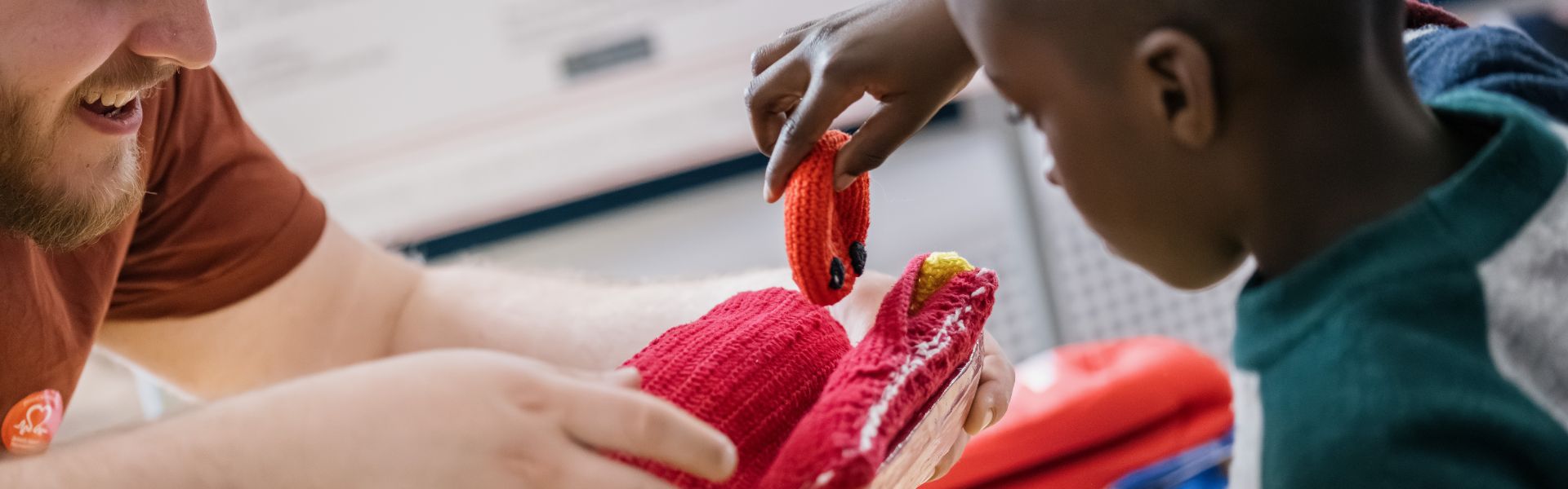 a young boy puts a crochet red blood cell into a crochet artery