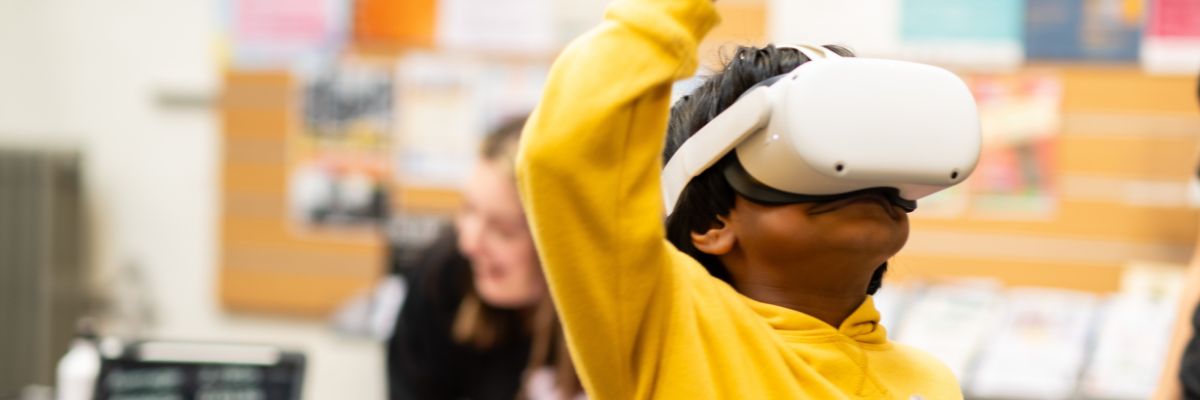 a boy in a yellow jumper wears a VR headset