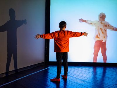 a boy stands in front of a screen and a computer generator image is created of him