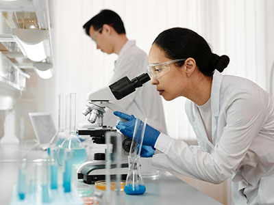 Researcher looking into a microscope.
