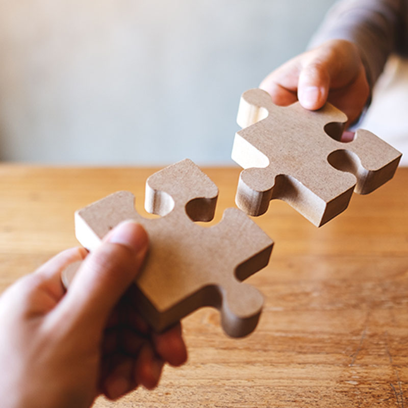 Two hands are placing a Jigsaw together