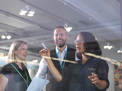 Staff brainstorming using a glass panel and marker pens