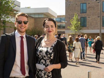 A well-dressed couple at graduation in front of the Great Hall