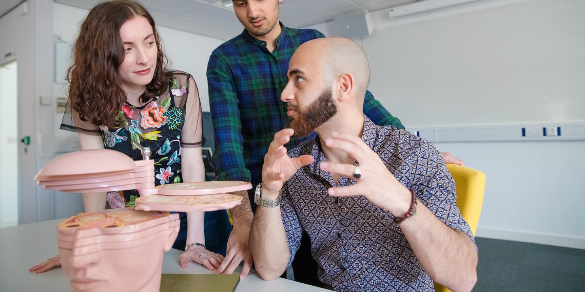 Three students clink glasses in a college bar.