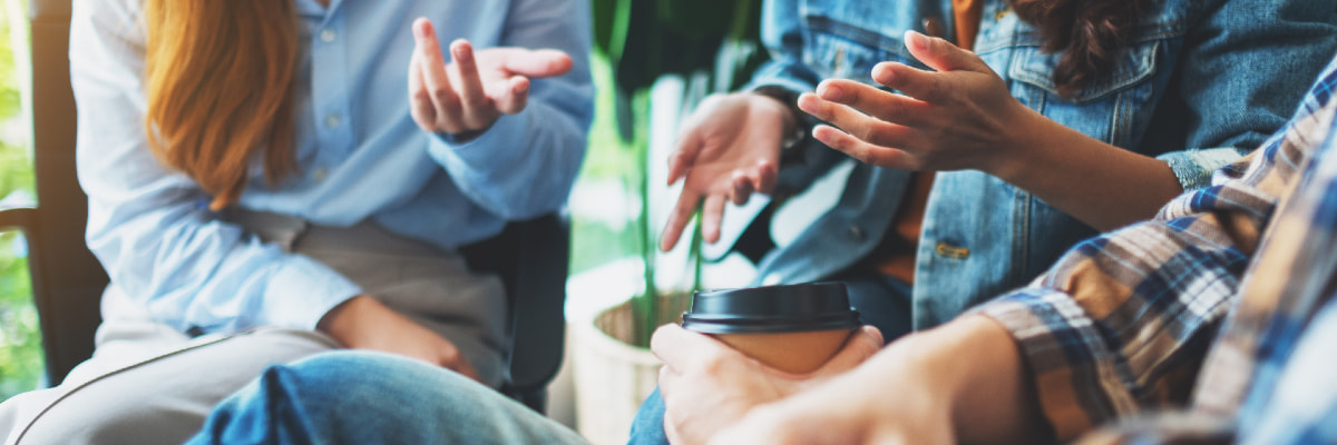 Three students walk along a path through a green field outside the Health Innovation building