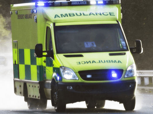 An ambulance with blue lights on driving along a road