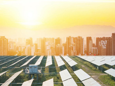 Solar panels in a field with tall city buildings on the horizon