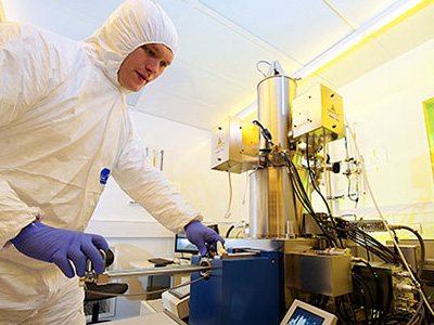 A technician in a protective suit operating laboratory equipment