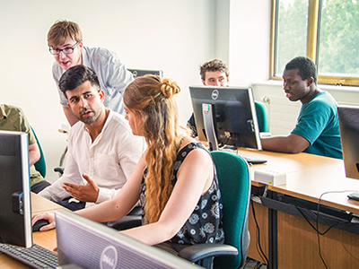 Students working together at computer screens