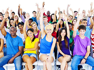 A large group of happy students, all with one arm raised