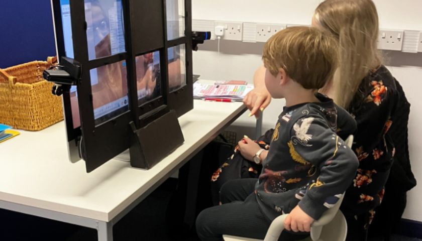 Wilbur sat on the knee of a researcher looking at  a screen